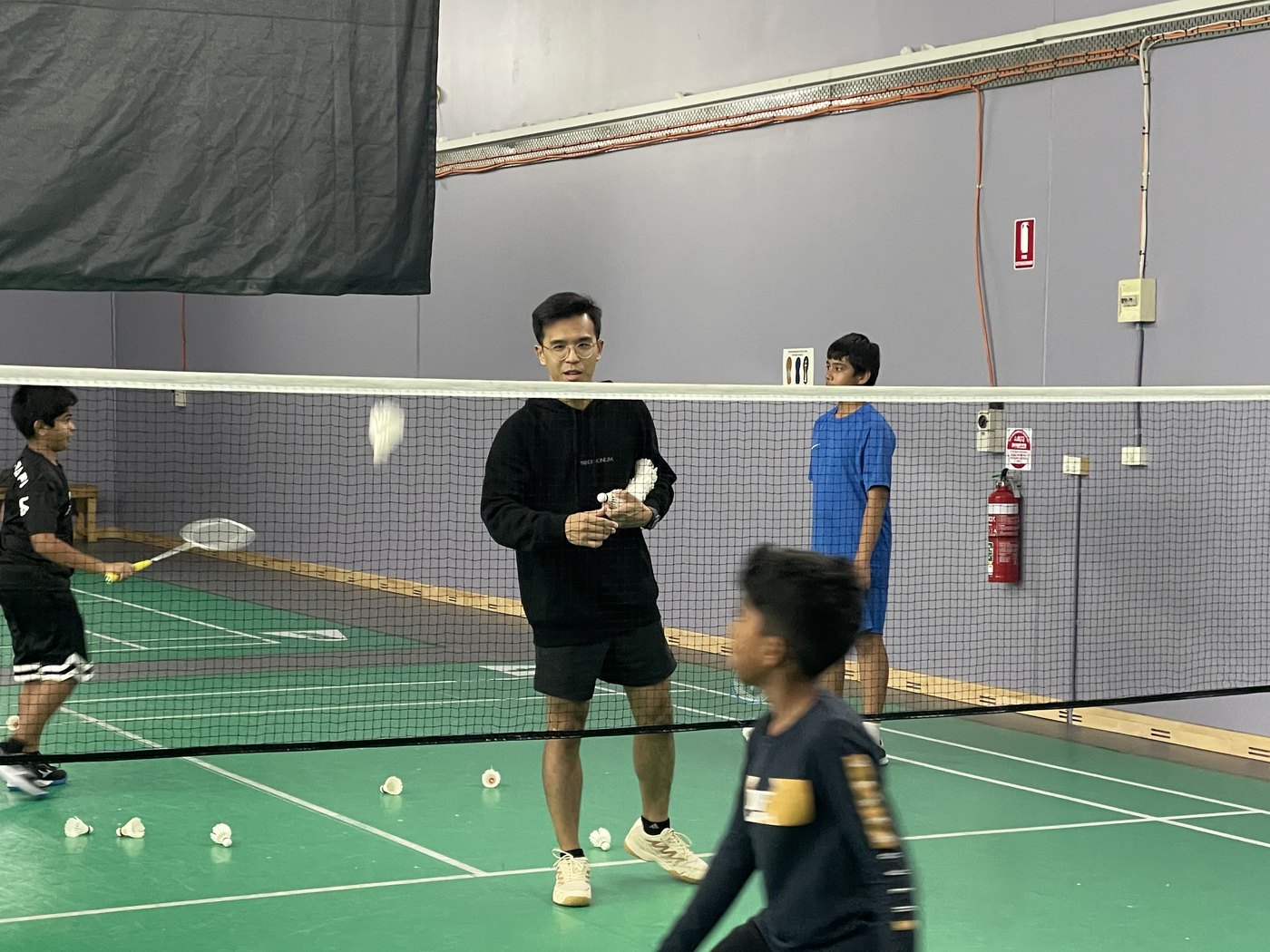 Coach demonstrating racket grip to a young badminton student