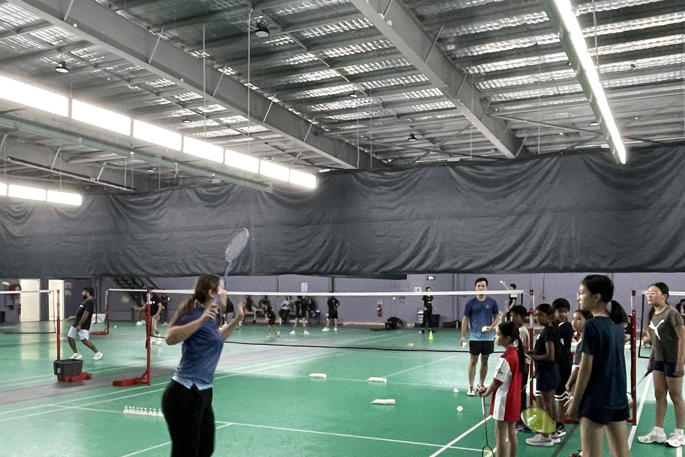 Junior badminton players completing footwork drills on court